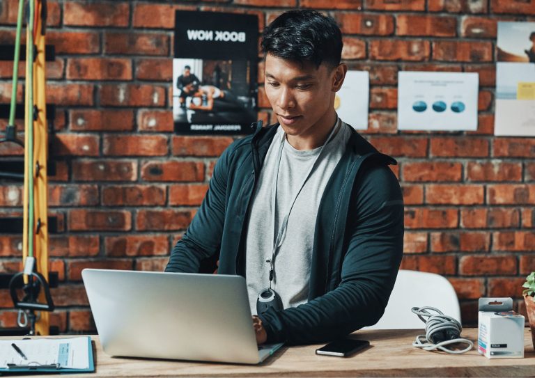 Image of a fitness trainer using a computer at his gym or exercise club