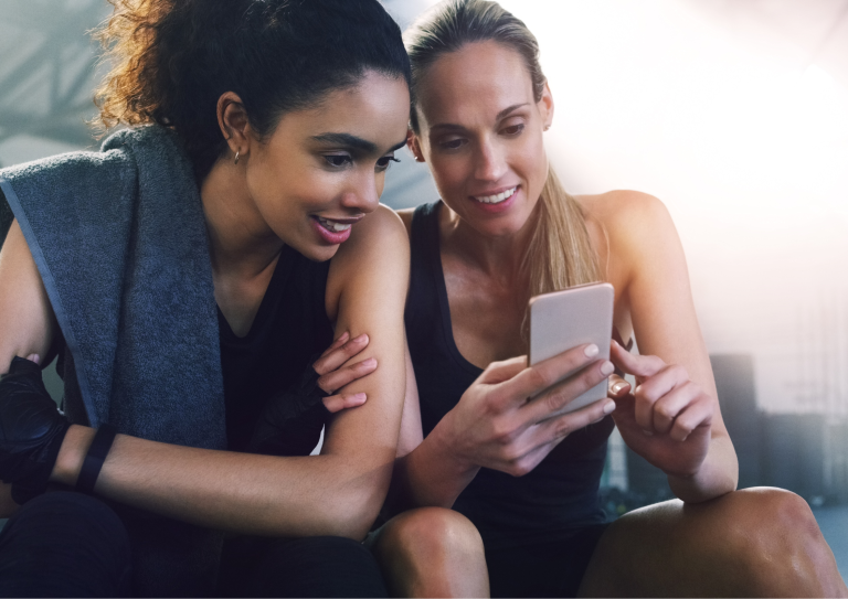 Image of two girls reading a fitness blog in the gym