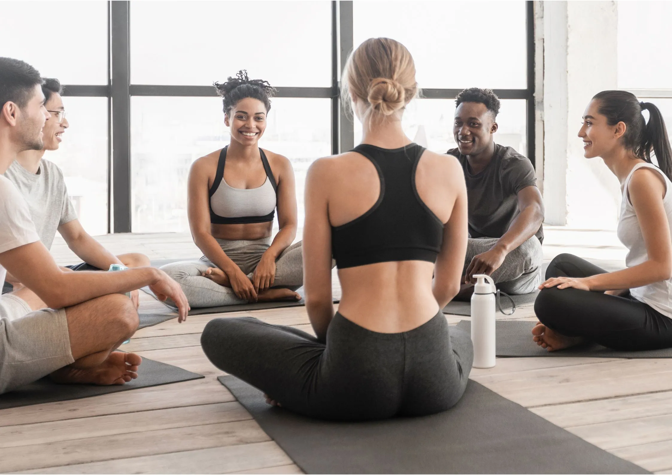 Image of gym members sitting in a circle on yoga mats