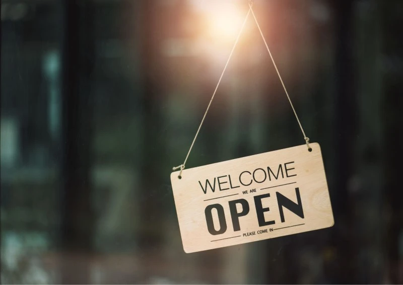 Image of a "welcome, we're open" sign displayed on a glass window of a gym or Fitness Training Studio